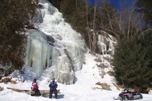 Snowmobilers in front of icicle rock cut